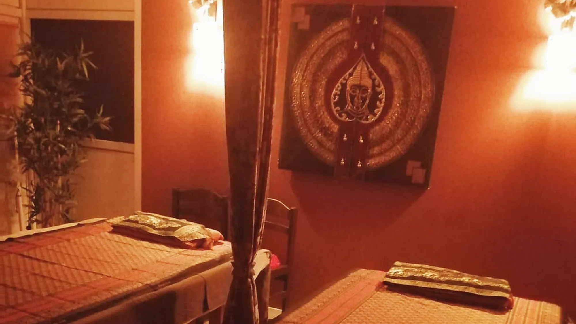 Treatment room at HomeSabay in Augsburg with Thai mats, wall lamps and carved woodwork