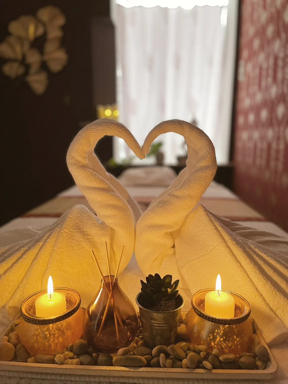 Folded towels on a freshly made couch, with candles beside them